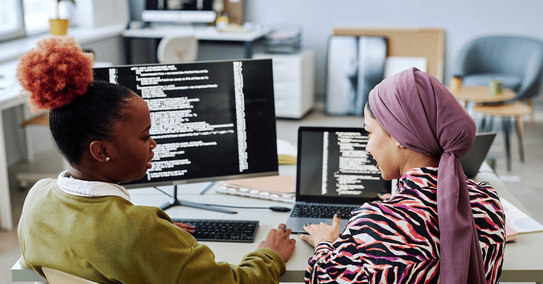 females working together on legacy software project shown on screen